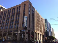 A photograph of the Twitter headquarters building in San Francisco with its @twitter sign seen from the street.