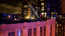 The illuminated X sign sits atop the company's headquarters building in San Francisco at night.