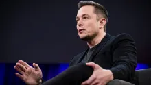 Elon Musk, owner of X and founder of SpaceXAI, speaking at a public event.