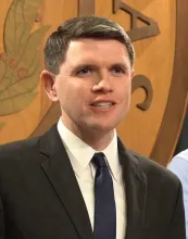 James Talarico speaking at a press conference in front of a Texas seal backdrop.