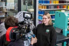 A camera operator filming a woman with a professional video camera during a video shoot.