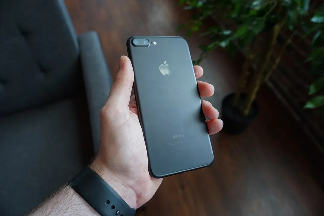 A hand holds a black smartphone indoors, the kind of phone screen where X users are now seeing the pointing-hand Promote prompt.