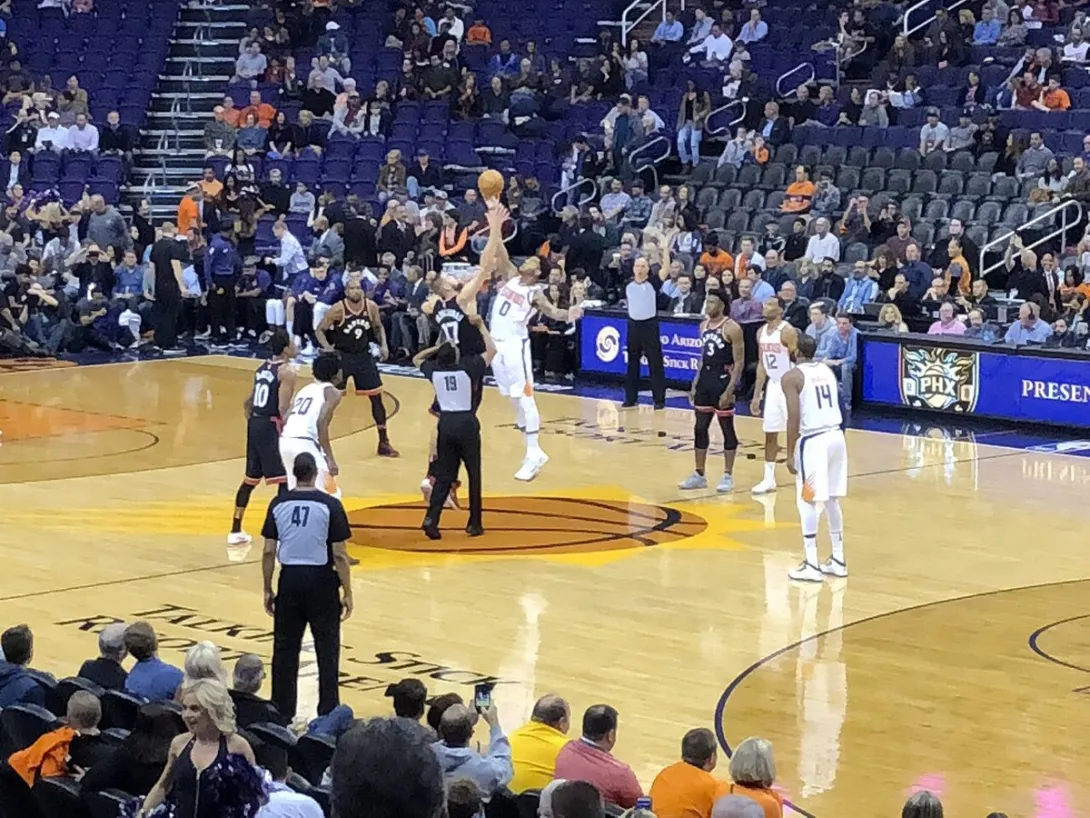 Toronto Raptors and Phoenix Suns players contest the opening tip-off of an NBA game in Phoenix.