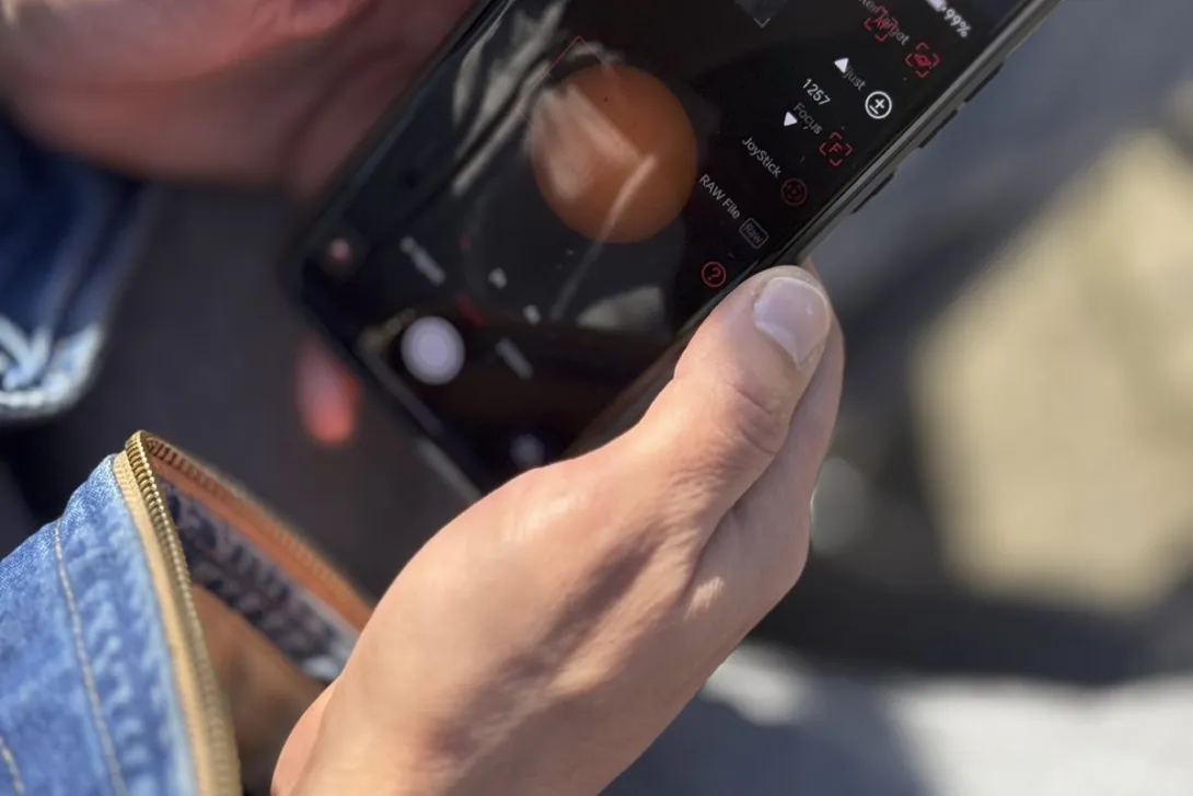 A person holding a smartphone outdoors with an app open on the screen.