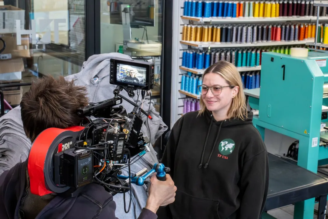 A camera operator filming a woman with a professional video camera during a video shoot.
